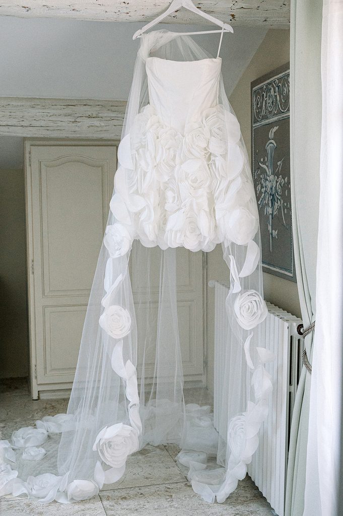 Robe de mariée courte et son voile long dans la chambre nuptiale du Mas de la Rose, lieu de réception de luxe en Provence