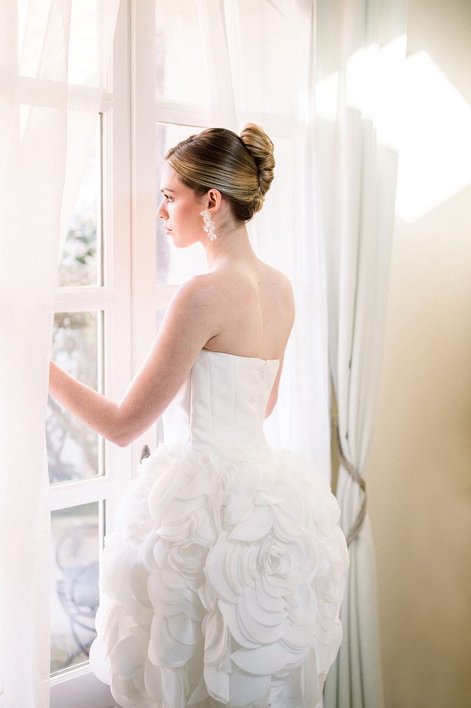 mariée qui regarde par la fenêtre de la chambre du Mas de la Rose, lieu de réception de mariage de luxe en Provence 