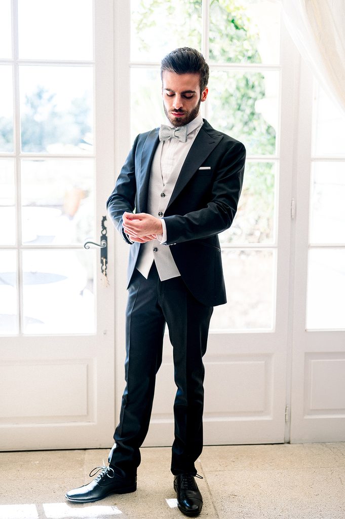marié debout qui ajuste son costume pendant ses préparatifs de mariage au Mas de la rose 