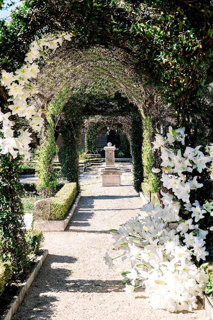 arche naturelle de mariage rehaussée de lys blancs pour une cérémonie de mariage en plein air au Mas de la Rose
