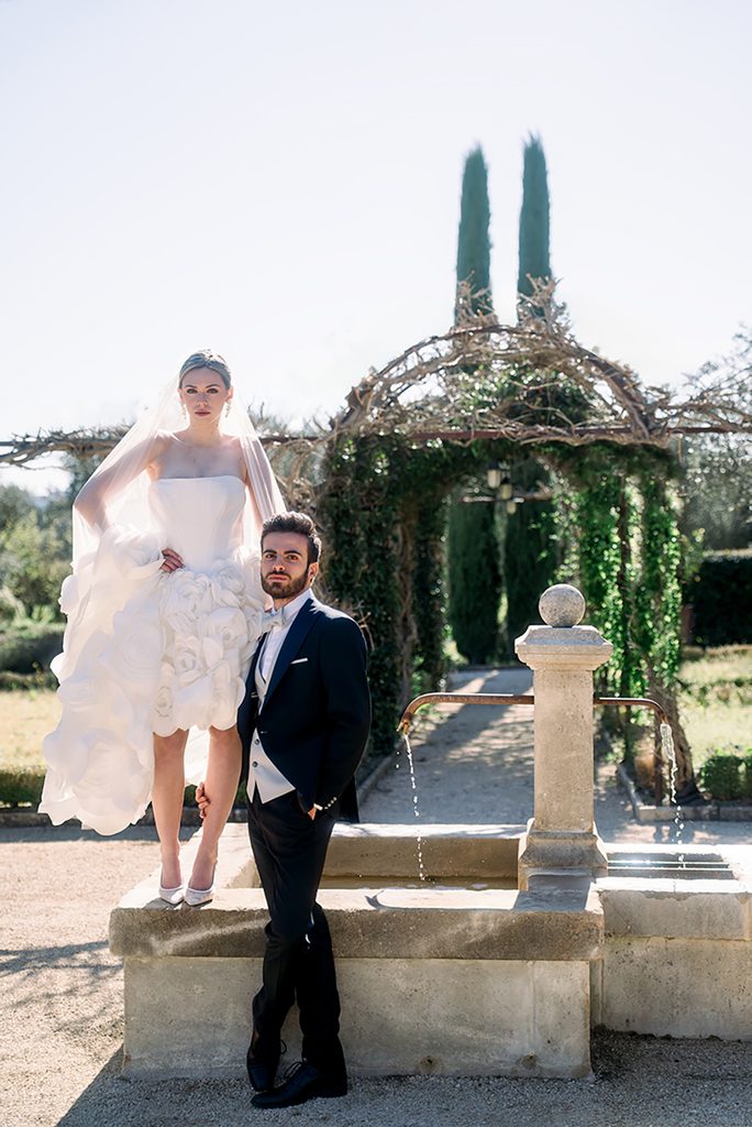 couple de mariés qui pose dans un style éditorial pendant leur séance de photos de couple dans le jardin du Mas de la Rose. La photo est prise par Aurore Stamper photographe de mariage de destination en Provence