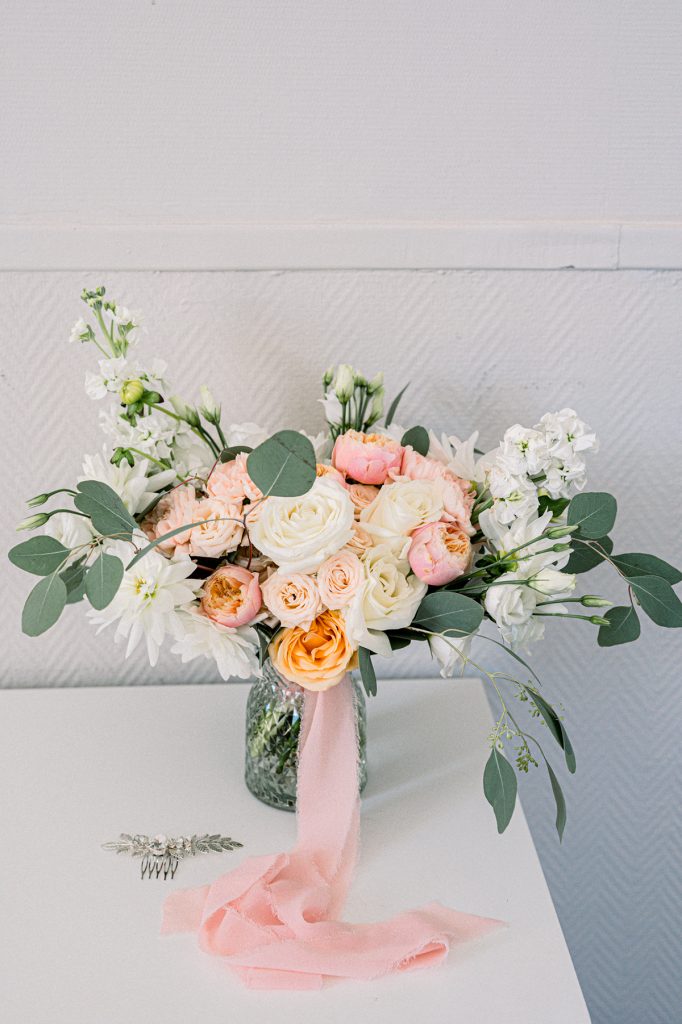 bouquet de mariée moderne de couleurs rose, orange et blanc posé dans une chambre du Castel Bay, domaine de mariage sur la Côte d'Azur